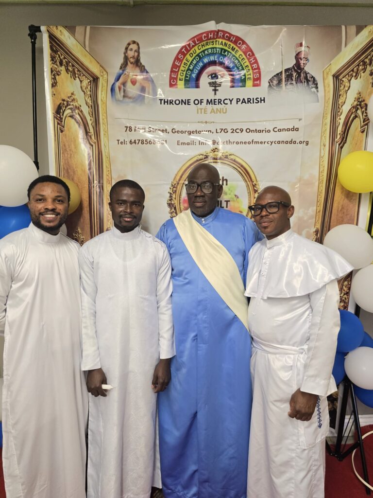 Four clergy members in white and blue garments in front of the harvest banner