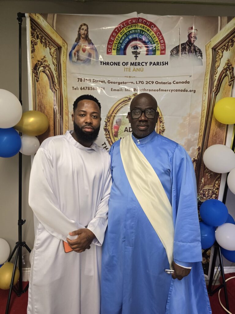 Two members in white and blue garments at the harvest banner