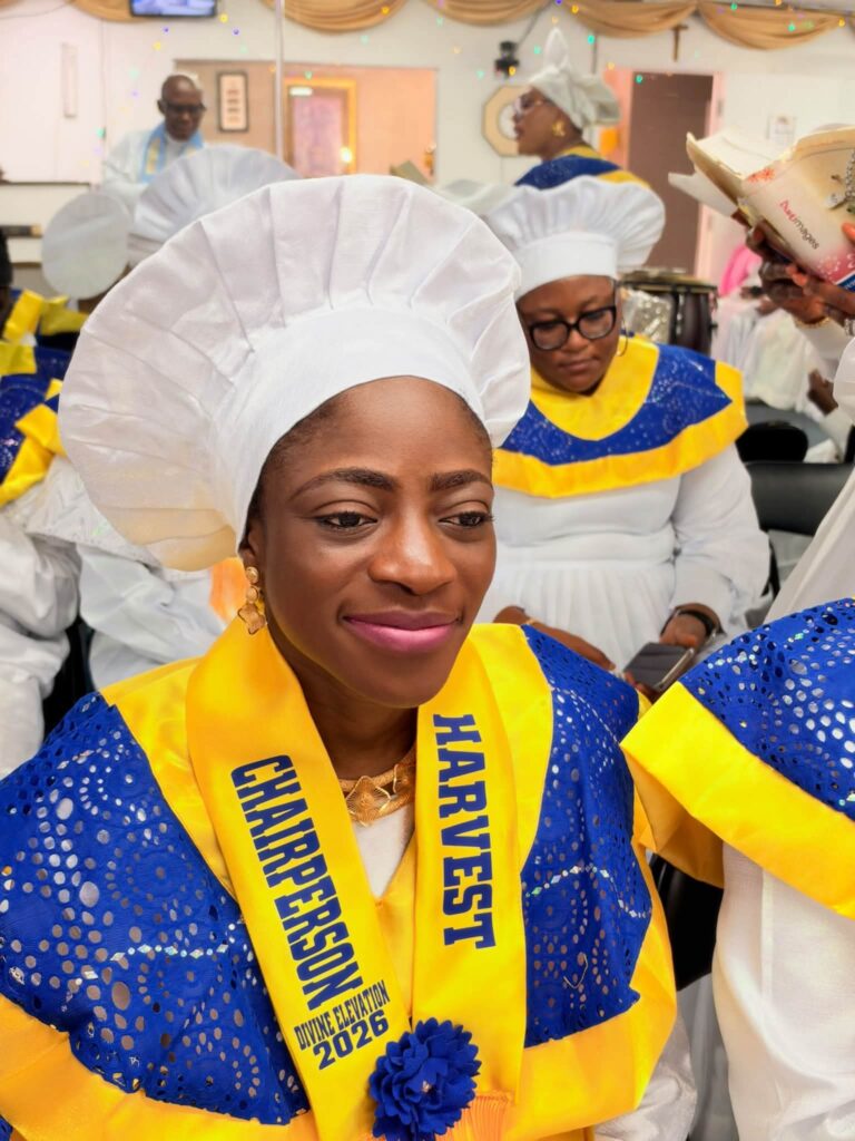 Harvest Chairperson in white head-tie with yellow Divine Elevation 2026 sash
