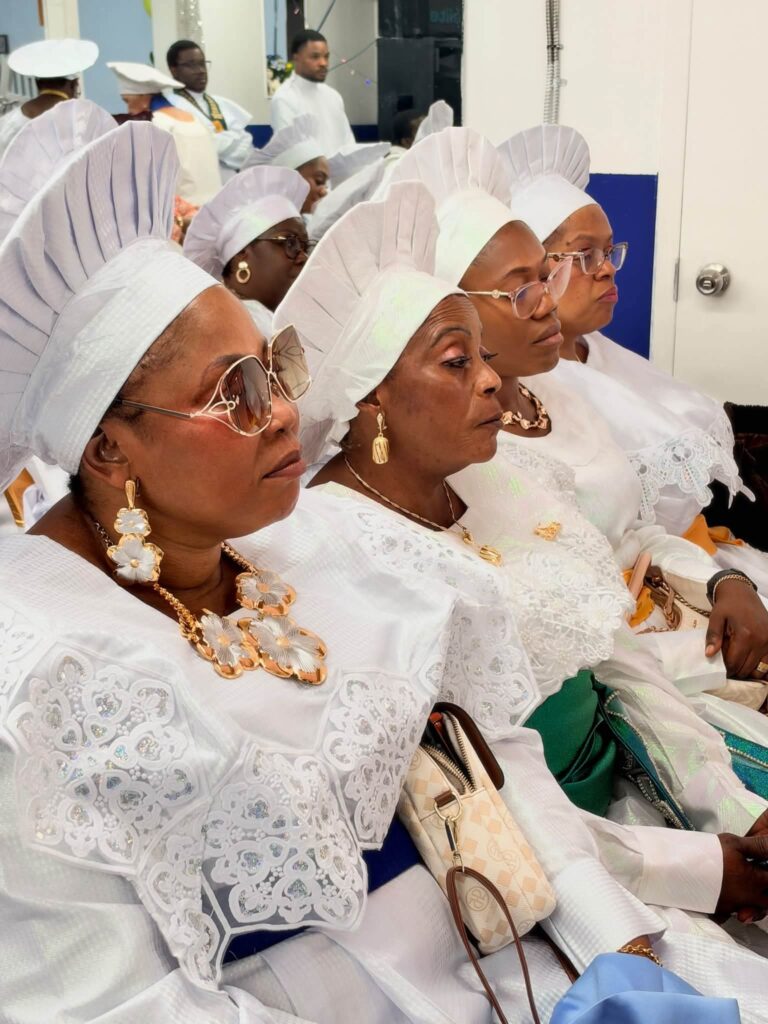 Women in white garments and head-ties seated during the service