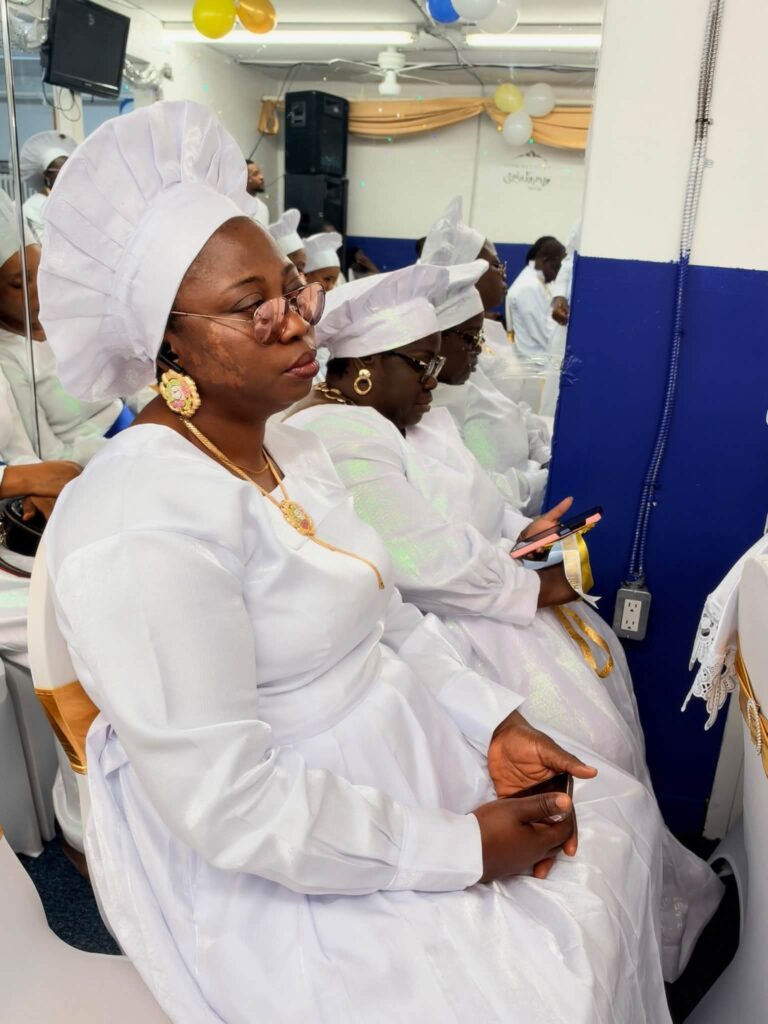 Women in white garments and head-ties seated during the service