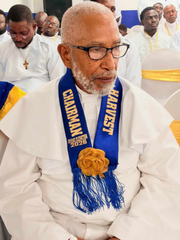 Harvest Chairman in white garment with blue Divine Elevation 2026 sash