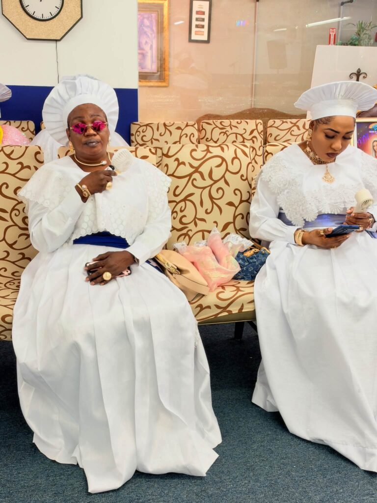 Two women in white garments and head-ties seated in the sanctuary